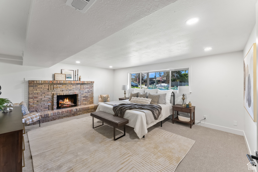 Carpeted bedroom with a brick fireplace and a textured ceiling