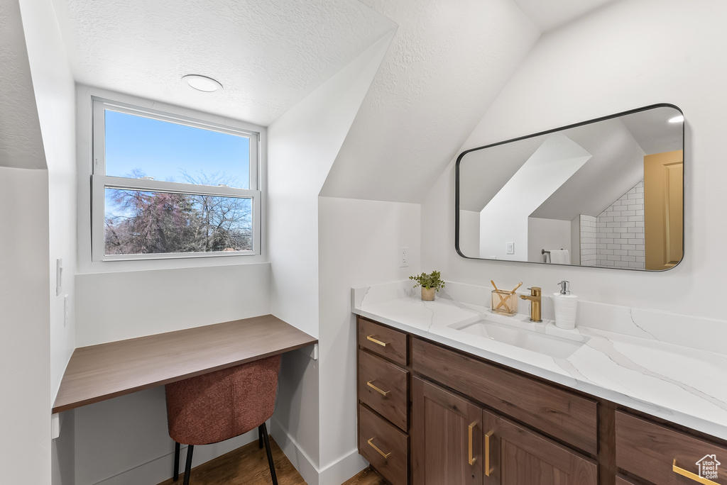 Bathroom featuring vaulted ceiling, vanity, and a textured ceiling