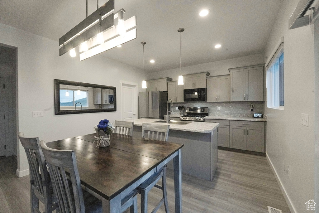 Interior space featuring pendant lighting, gray cabinets, dark wood-type flooring, stainless steel appliances, and tasteful backsplash