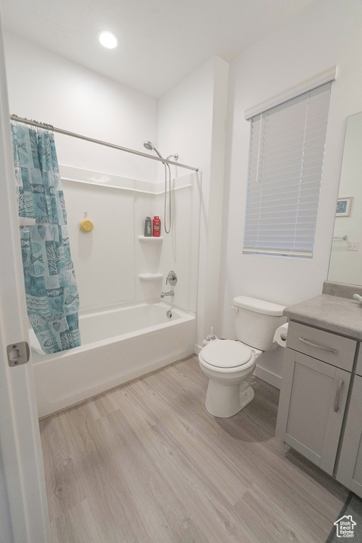 Full bathroom featuring hardwood / wood-style floors, vanity, shower / bath combination with curtain, and toilet