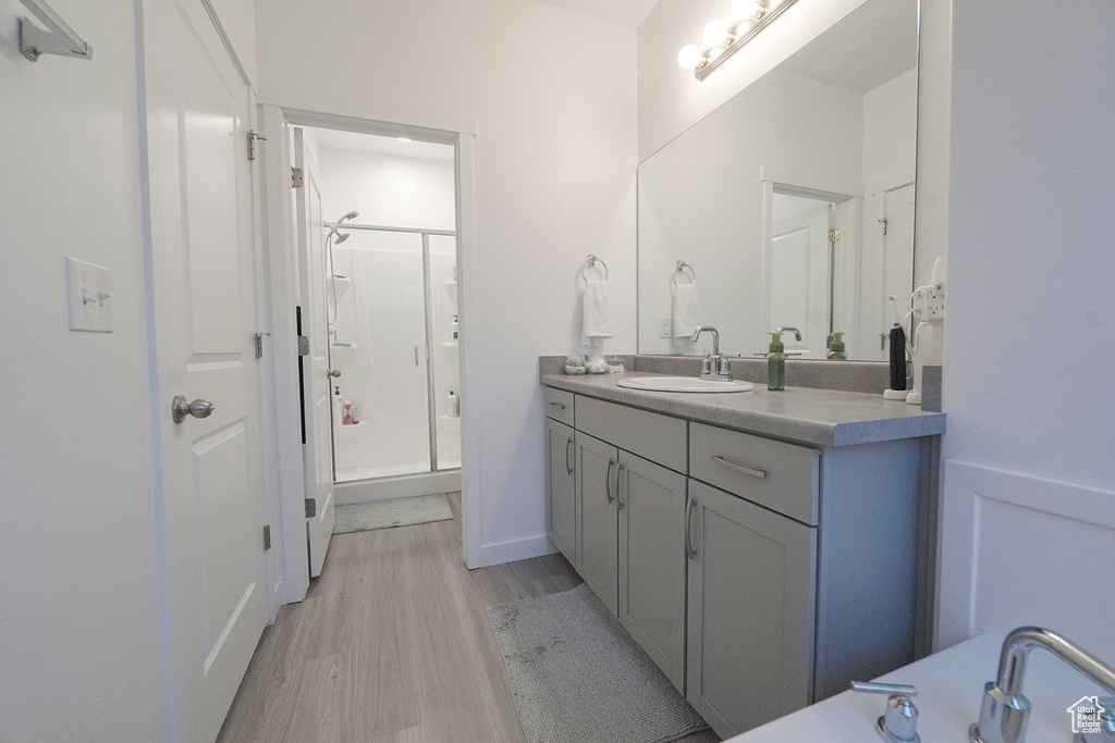 Bathroom featuring hardwood / wood-style floors, walk in shower, and vanity