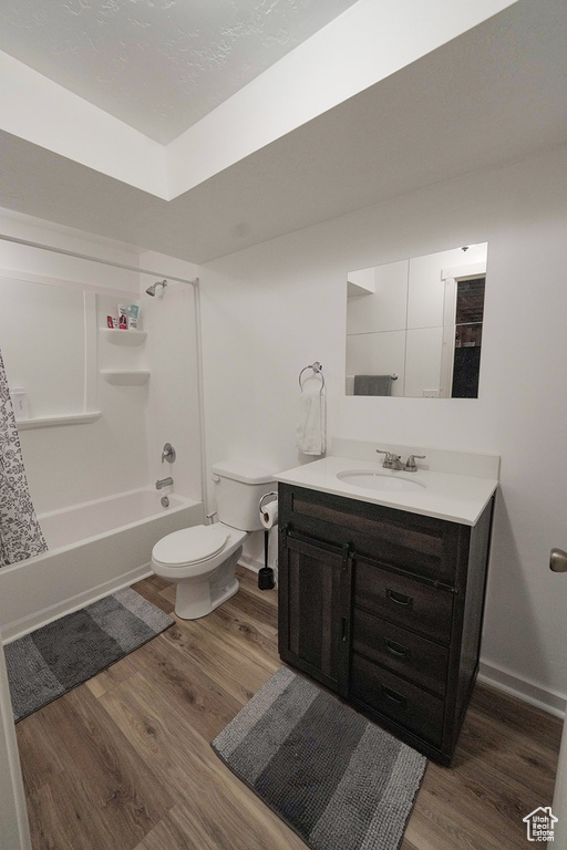 Full bathroom featuring hardwood / wood-style floors, vanity, toilet, and shower / tub combo with curtain
