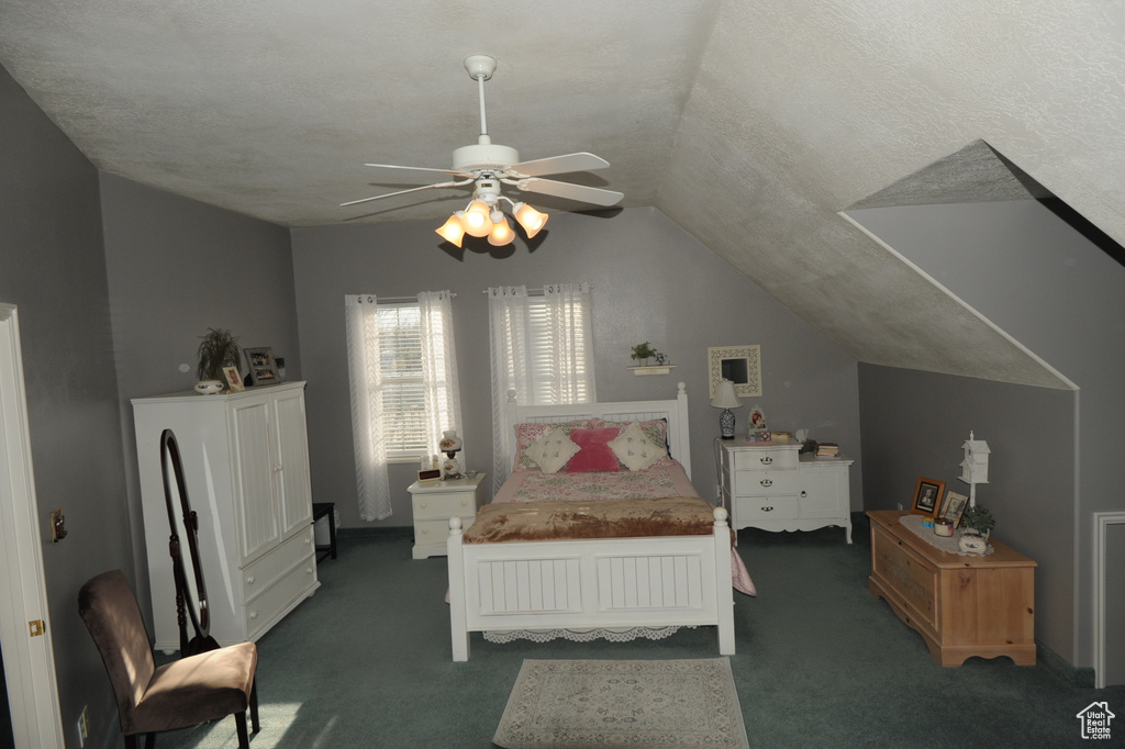 Bedroom with a textured ceiling, vaulted ceiling, ceiling fan, and dark colored carpet