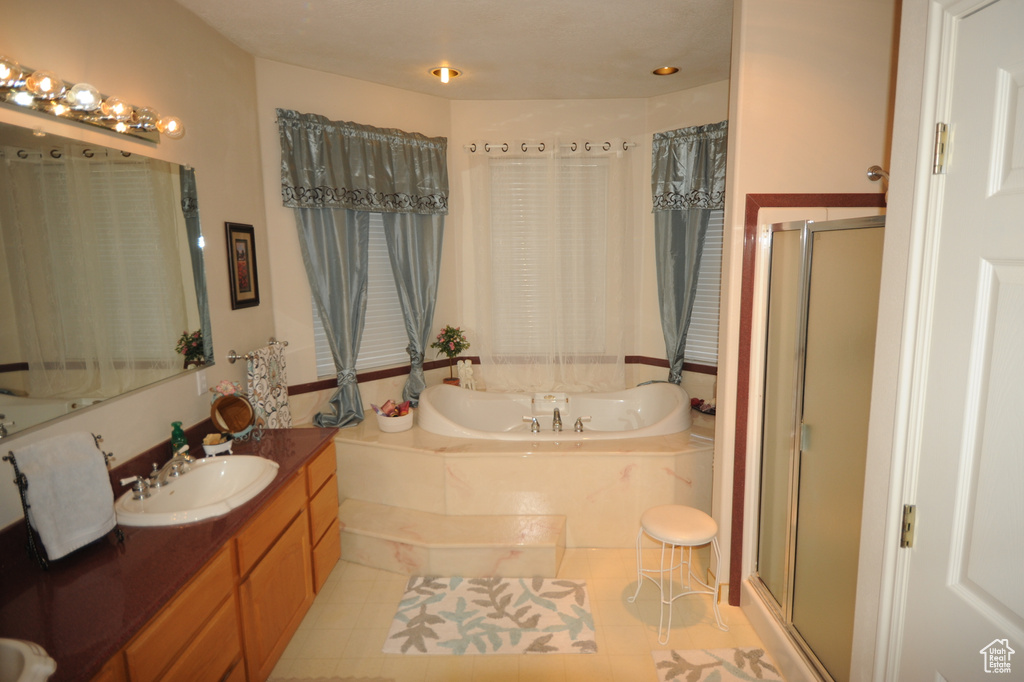 Bathroom with oversized vanity, independent shower and bath, and tile flooring