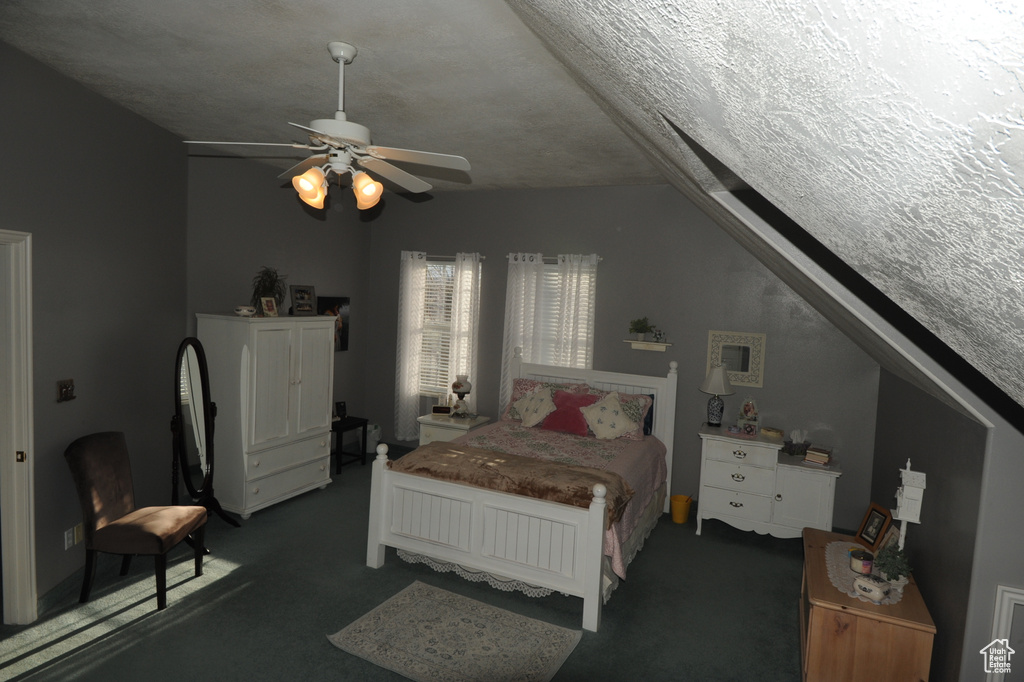 Bedroom with lofted ceiling, ceiling fan, dark carpet, and a textured ceiling