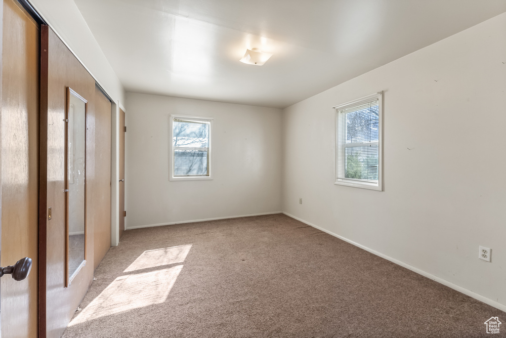 Unfurnished bedroom featuring light colored carpet and multiple windows