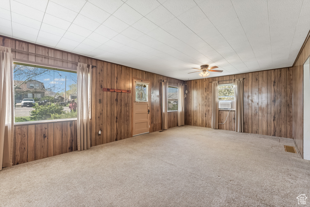 Carpeted empty room with ceiling fan and wooden walls
