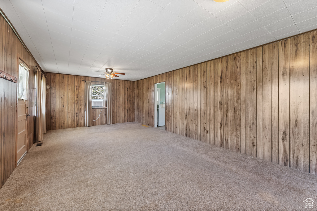 Unfurnished room featuring wood walls, ceiling fan, and carpet flooring