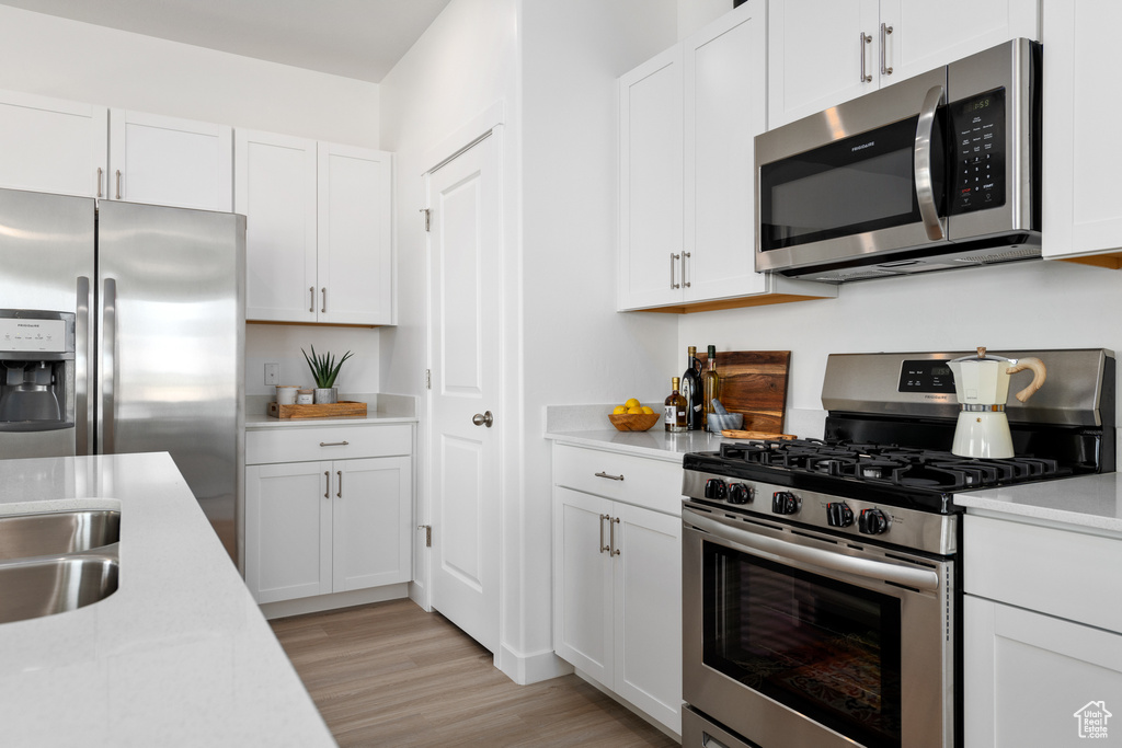Kitchen featuring white cabinets, light hardwood / wood-style floors, and appliances with stainless steel finishes