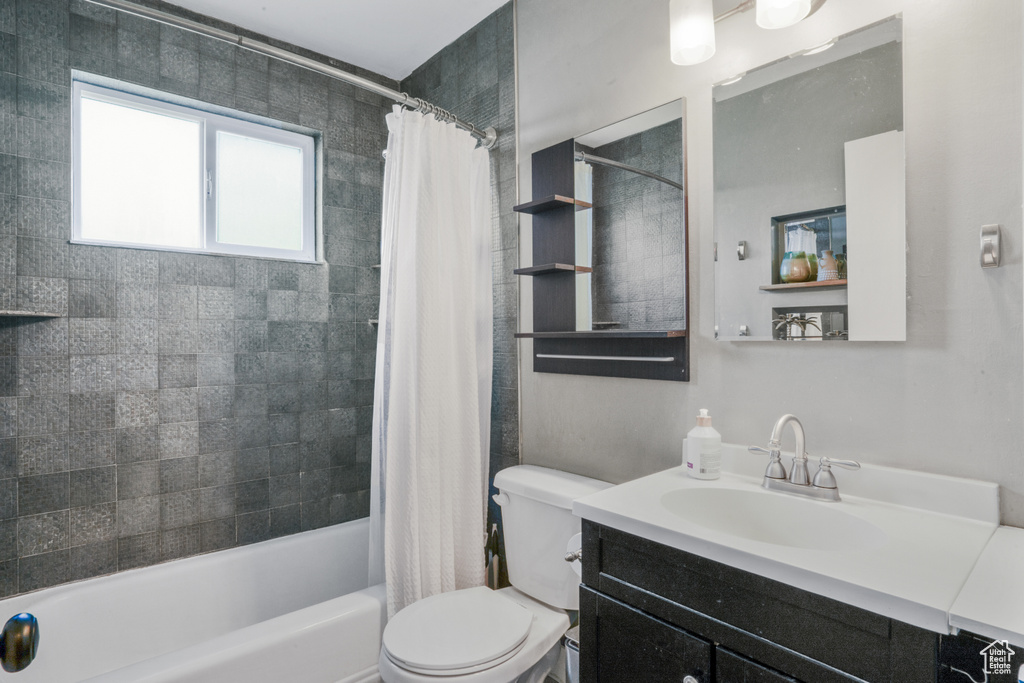 Full bathroom with shower / tub combo, vanity with extensive cabinet space, and toilet