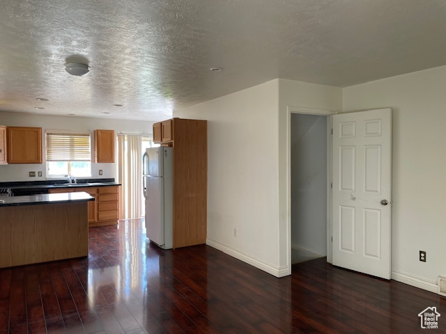 Kitchen featuring a textured ceiling, dark wood-type flooring, and white refrigerator