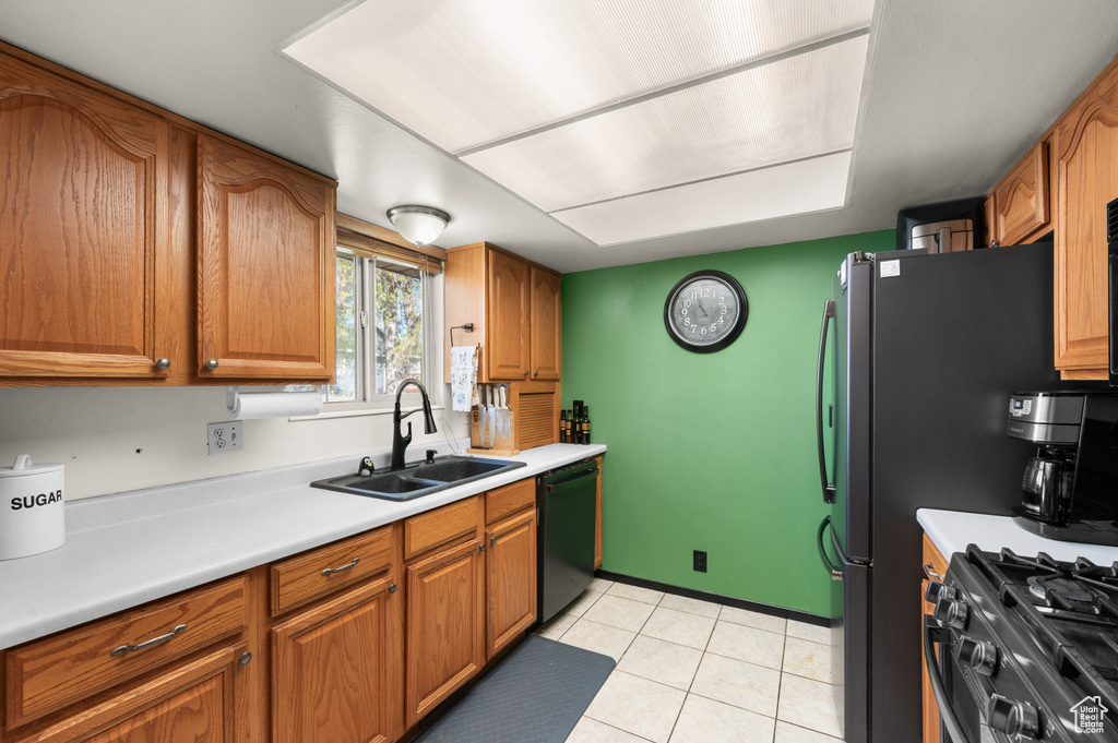 Kitchen with sink, black dishwasher, and light tile floors