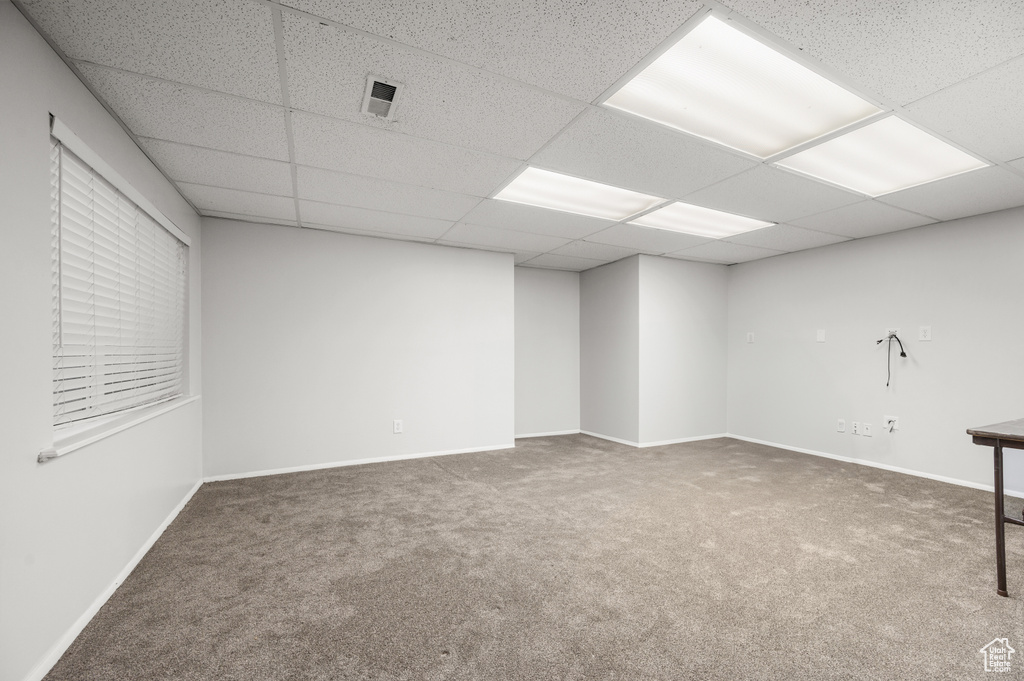 Empty room with dark colored carpet and a paneled ceiling