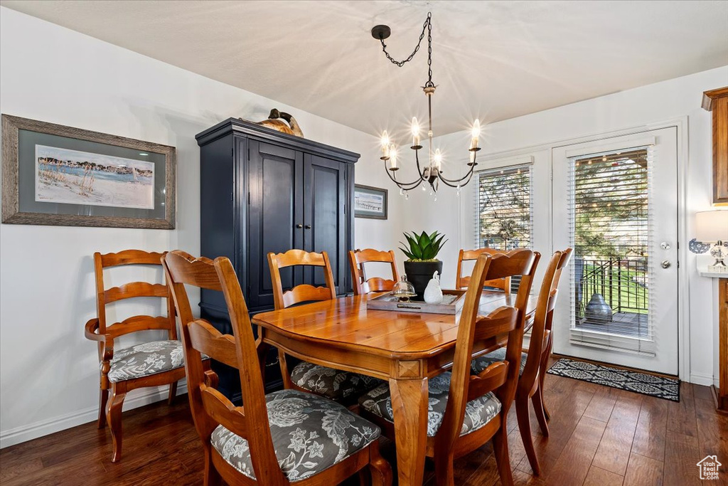 Dining room with a notable chandelier and dark hardwood / wood-style floors