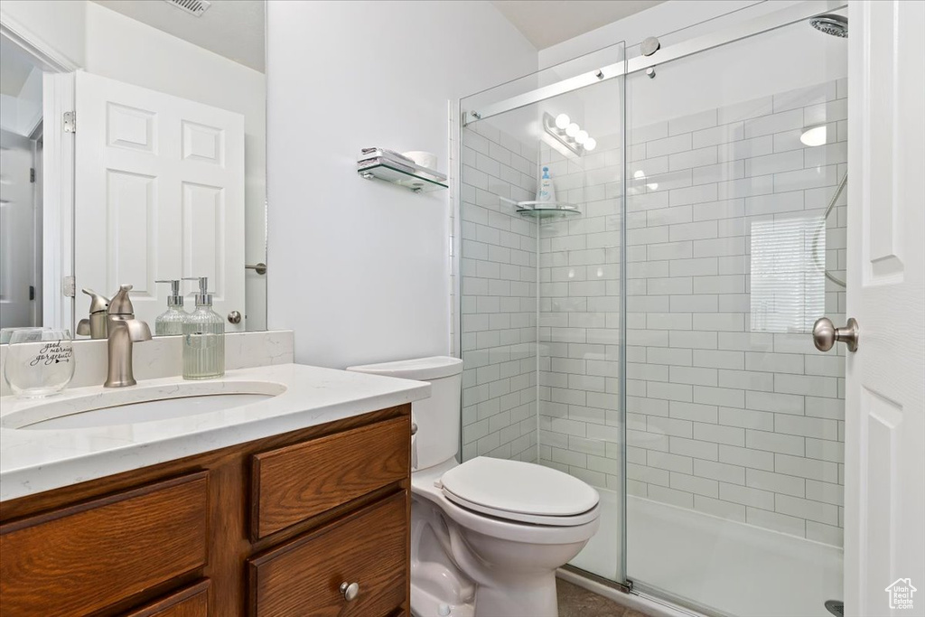 Bathroom with an enclosed shower, vanity, and toilet
