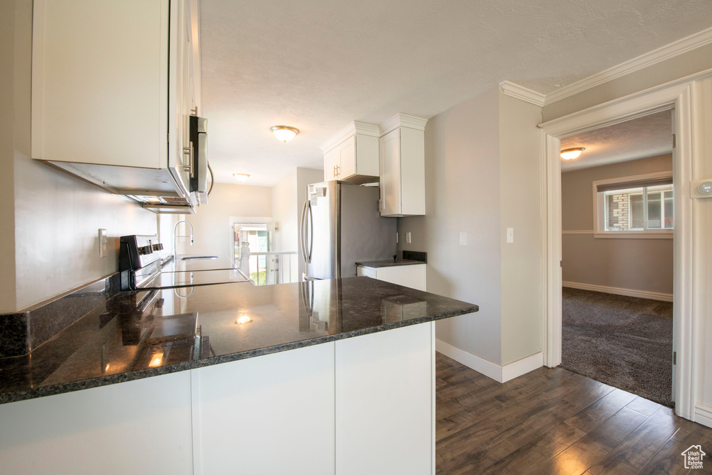 Kitchen featuring kitchen peninsula, white cabinetry, dark wood-type flooring, range, and dark stone countertops
