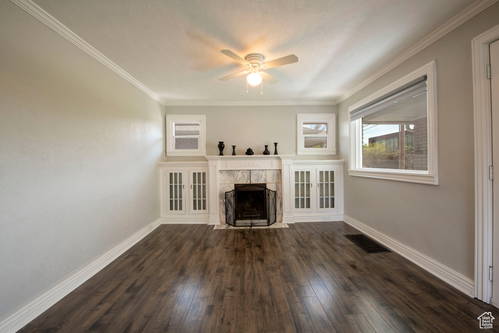 Unfurnished living room with ceiling fan, crown molding, a tile fireplace, and dark hardwood / wood-style floors