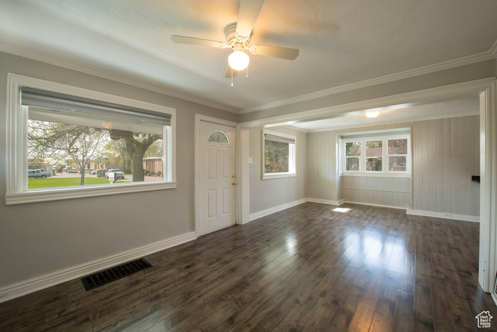 Unfurnished room featuring dark hardwood / wood-style flooring, ceiling fan, crown molding, and a wealth of natural light
