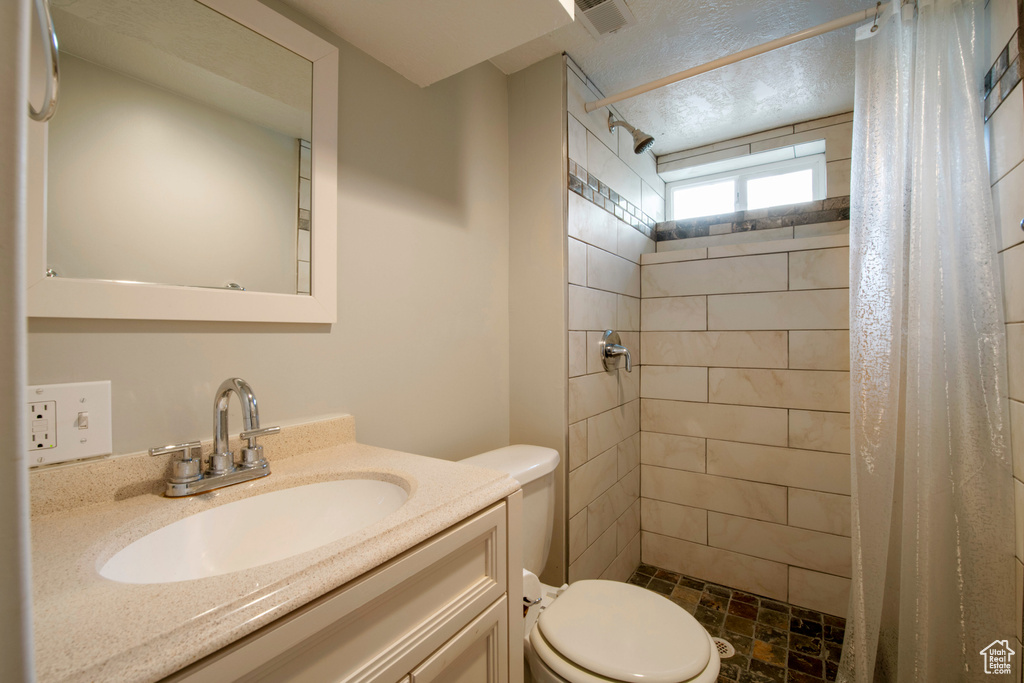Bathroom featuring vanity with extensive cabinet space, toilet, and a shower with curtain