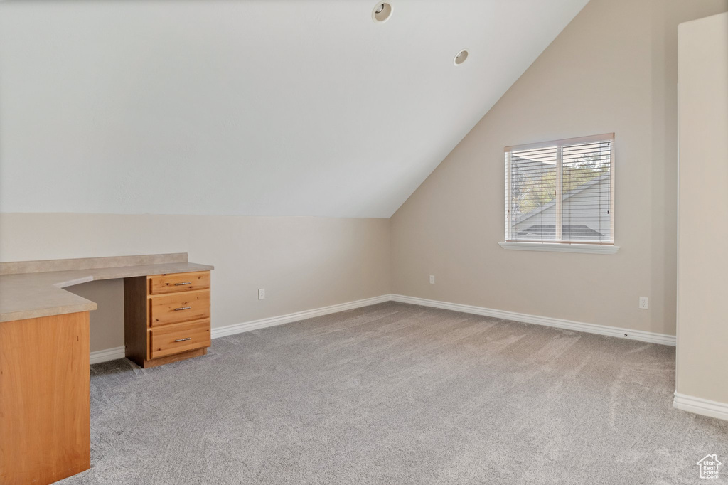 Additional living space featuring light colored carpet and lofted ceiling