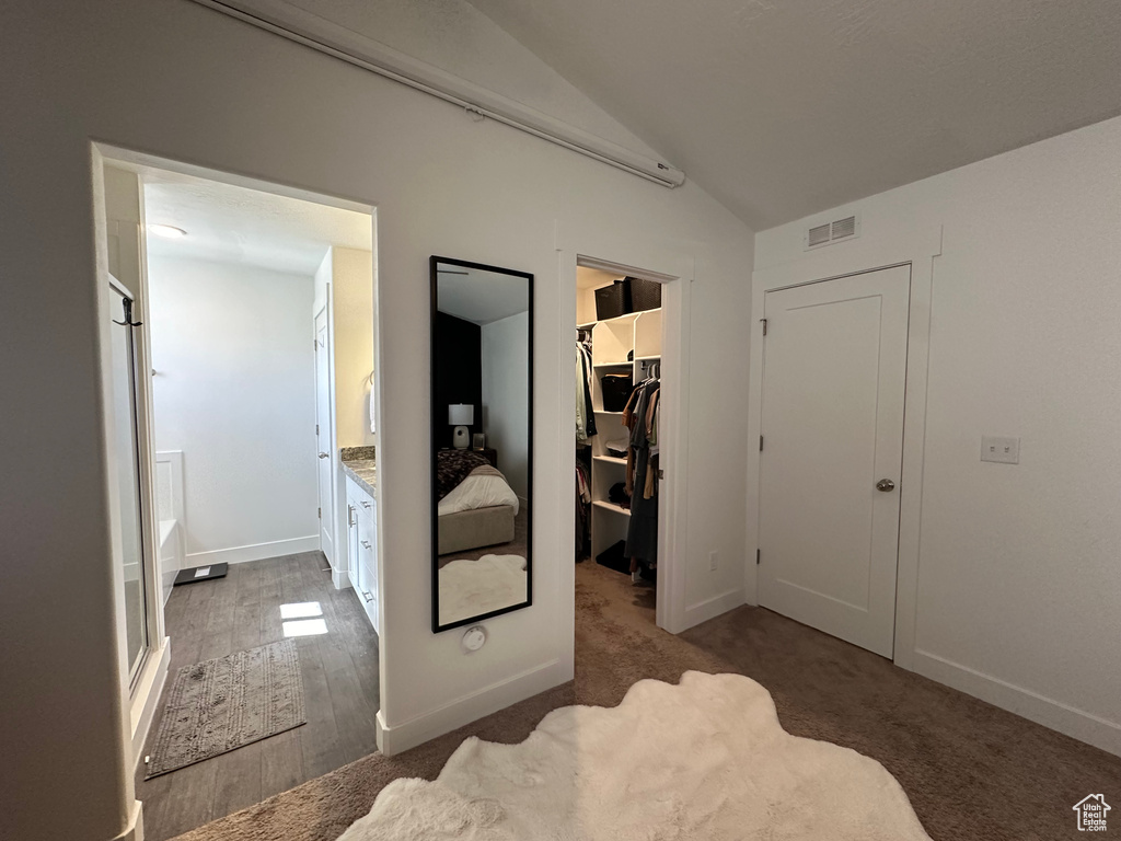 Carpeted bedroom featuring a closet, a spacious closet, and lofted ceiling