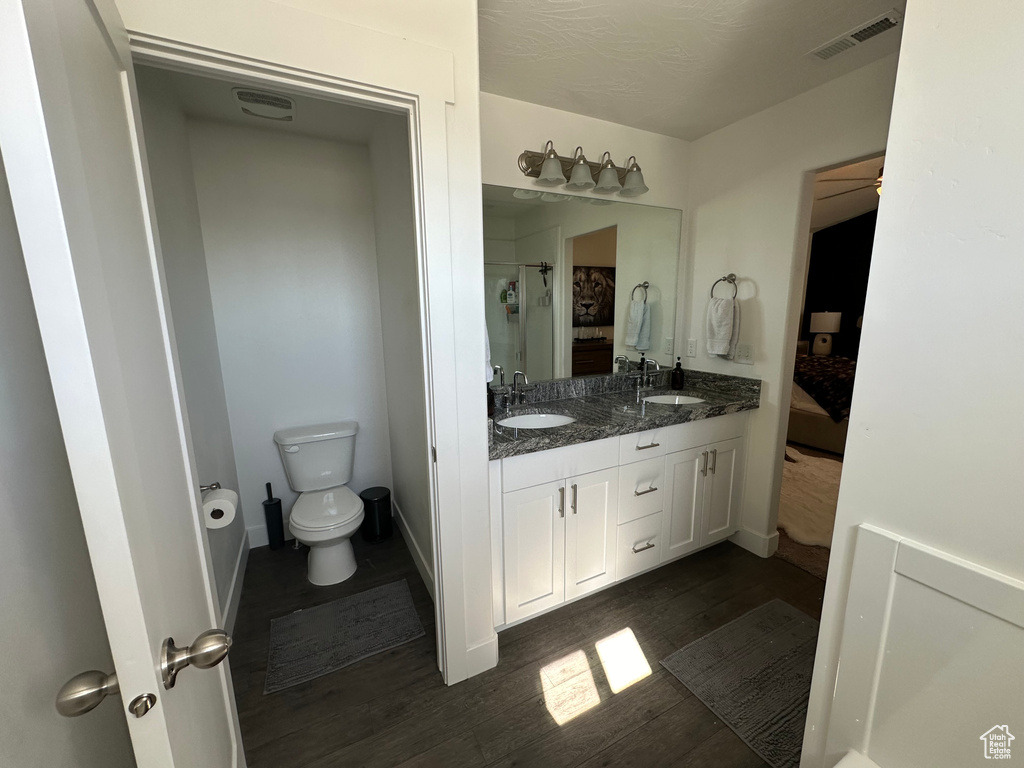 Bathroom with wood-type flooring, ceiling fan, toilet, and dual bowl vanity