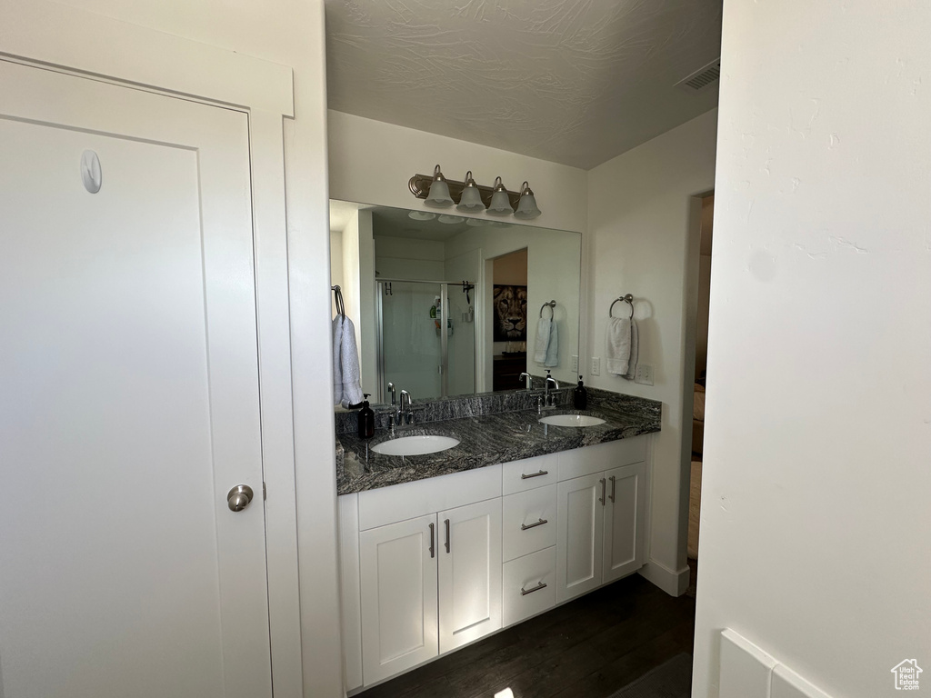 Bathroom featuring dual sinks, hardwood / wood-style floors, and vanity with extensive cabinet space
