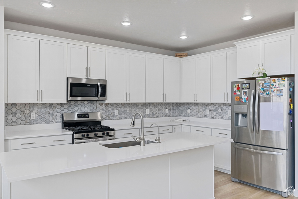 Kitchen featuring a center island with sink, sink, appliances with stainless steel finishes, and white cabinetry