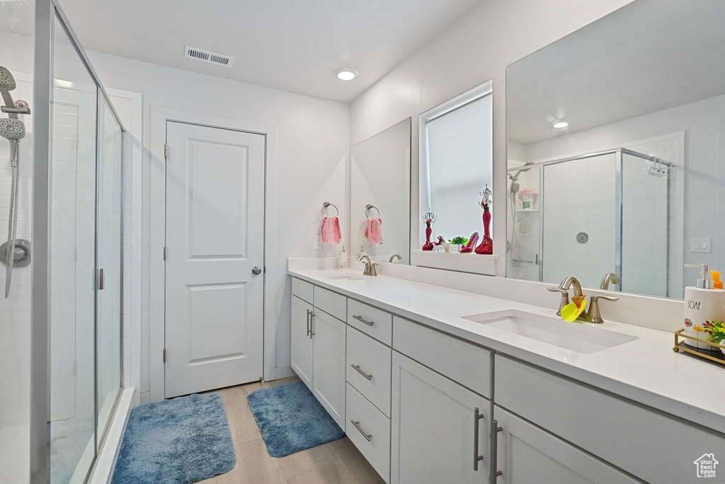 Bathroom featuring large vanity, an enclosed shower, double sink, and tile flooring