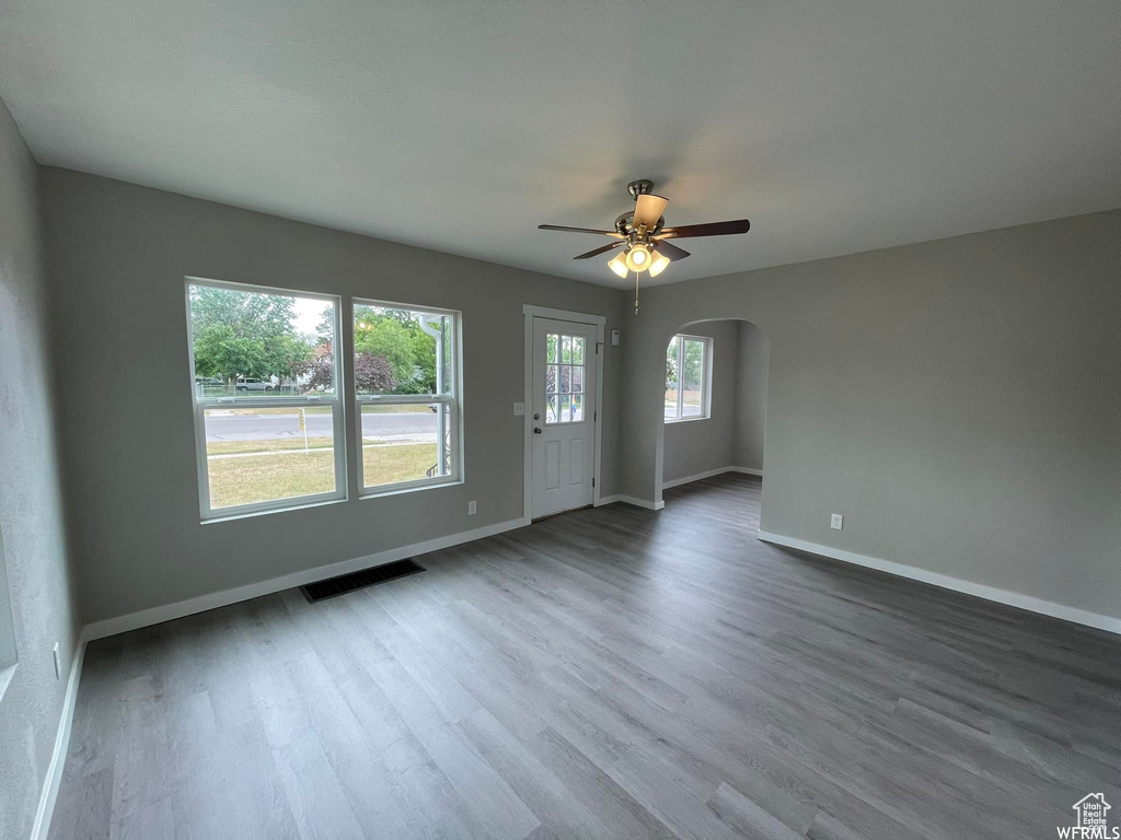 Empty room with dark hardwood / wood-style flooring, plenty of natural light, and ceiling fan