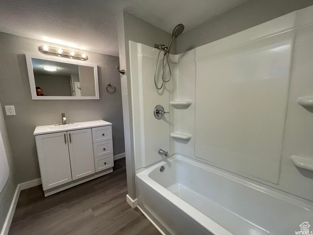 Bathroom featuring hardwood / wood-style floors, shower / bath combination, vanity, and a textured ceiling