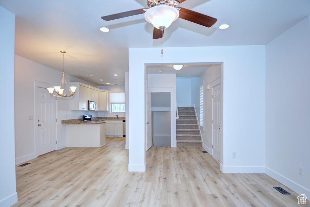 Interior space featuring ceiling fan with notable chandelier and light hardwood / wood-style flooring
