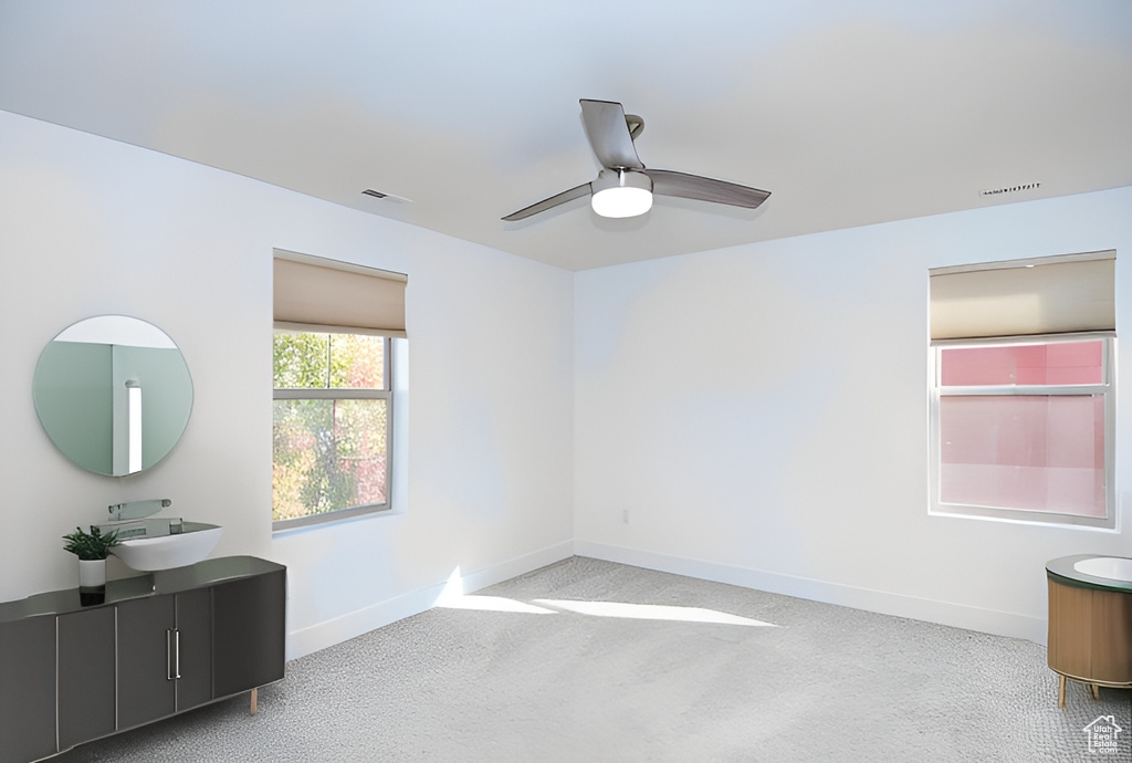 Empty room featuring sink, ceiling fan, and light carpet