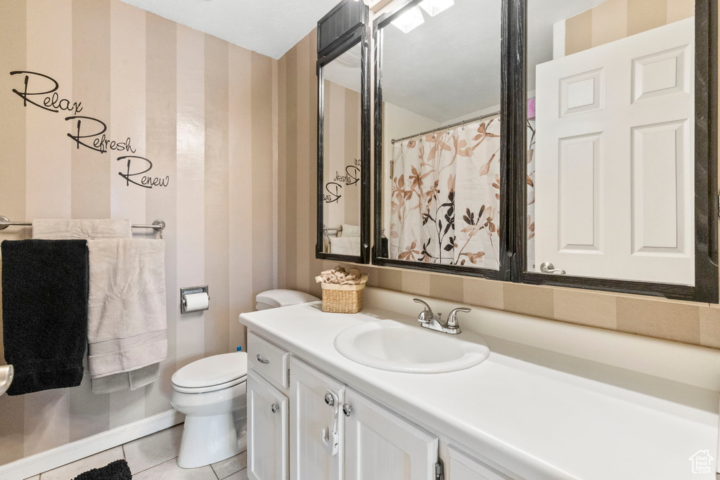 Bathroom featuring tile floors, vanity with extensive cabinet space, and toilet