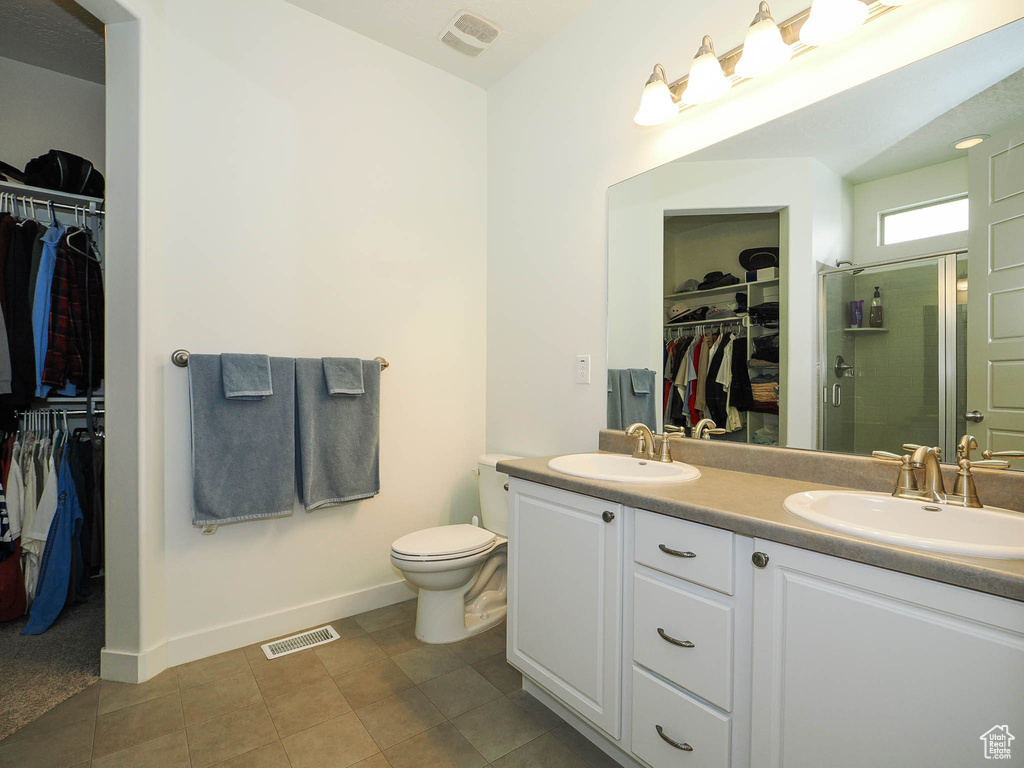 Bathroom with a shower with door, oversized vanity, toilet, double sink, and tile floors