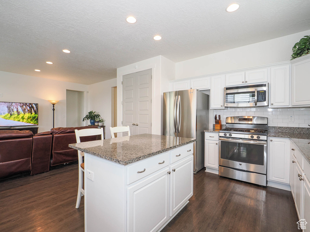 Kitchen with a center island, tasteful backsplash, stainless steel appliances, and dark hardwood / wood-style floors