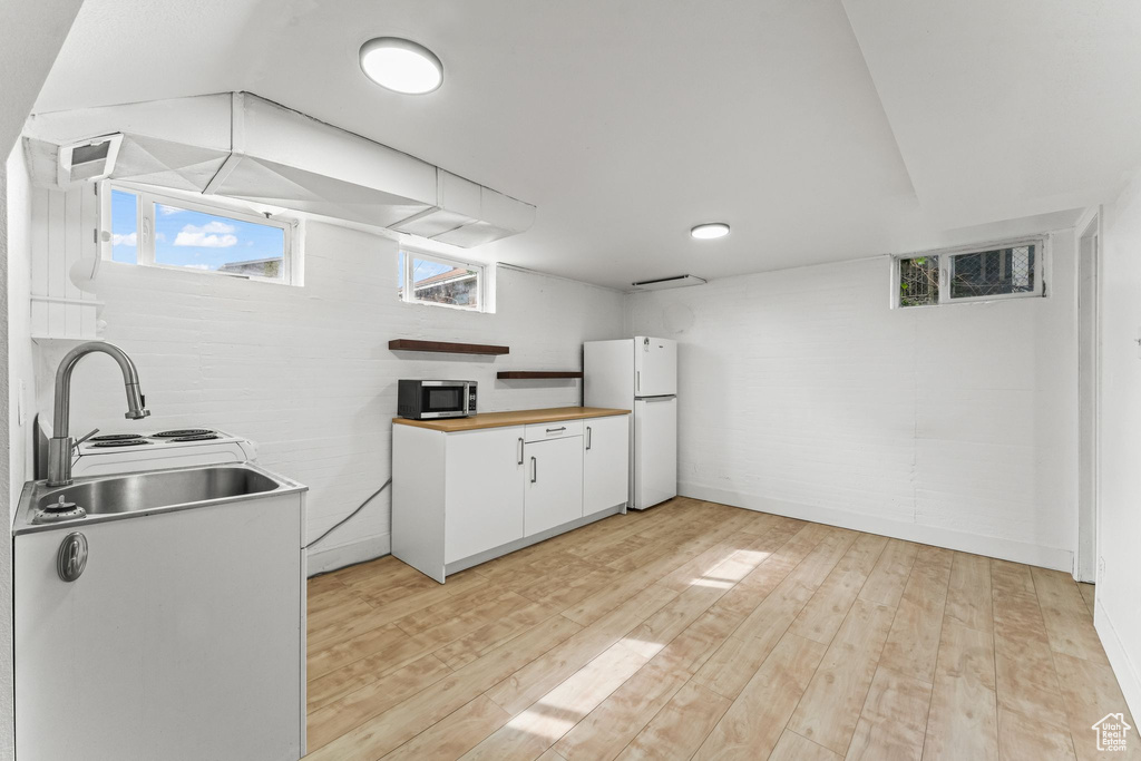 Kitchen with white fridge, light hardwood / wood-style flooring, sink, and white cabinetry