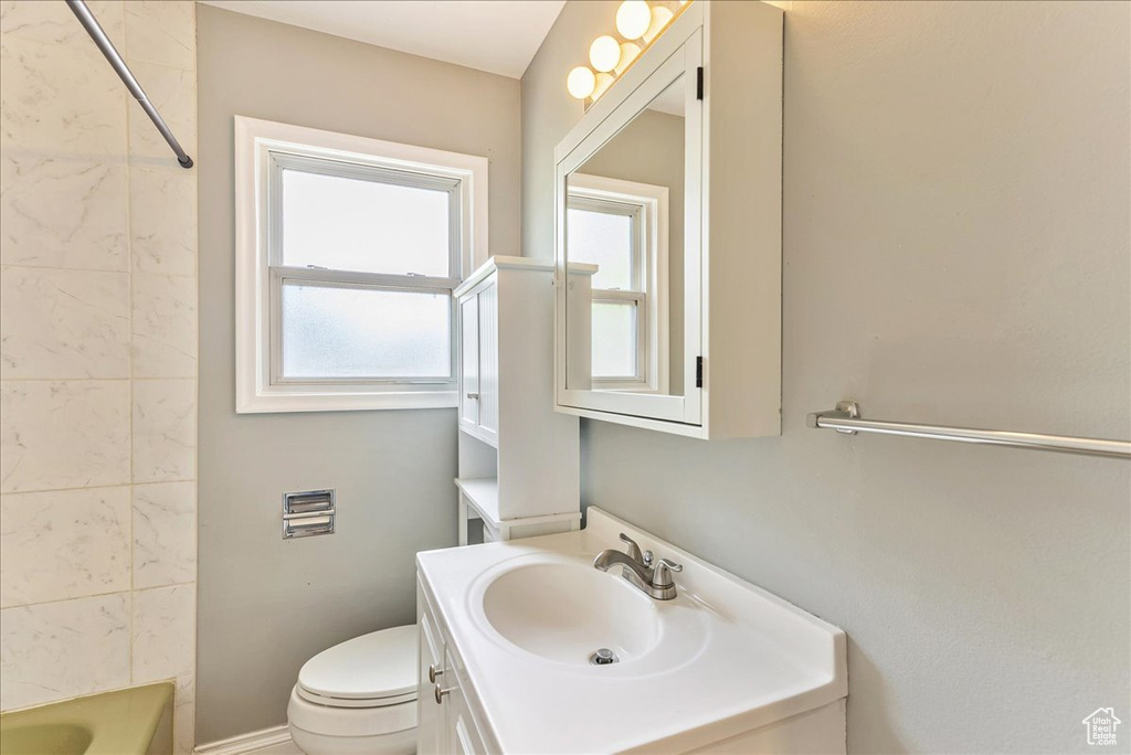 Full bathroom featuring plenty of natural light, vanity, tiled shower / bath combo, and toilet
