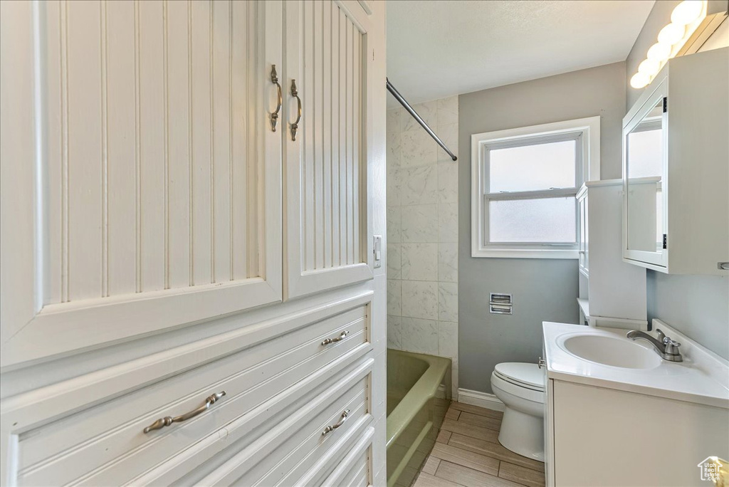 Full bathroom with tiled shower / bath combo, large vanity, and toilet