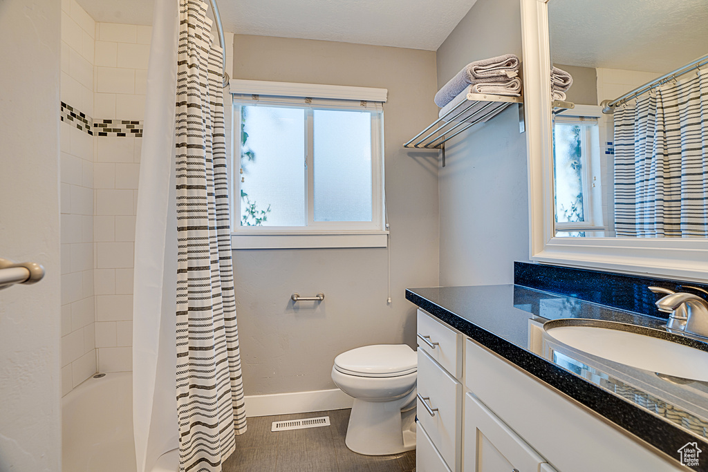 Full bathroom with vanity with extensive cabinet space, toilet, and shower / bath combination with curtain