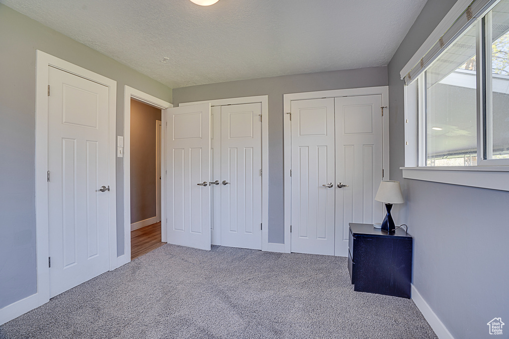 Unfurnished bedroom featuring light colored carpet and two closets