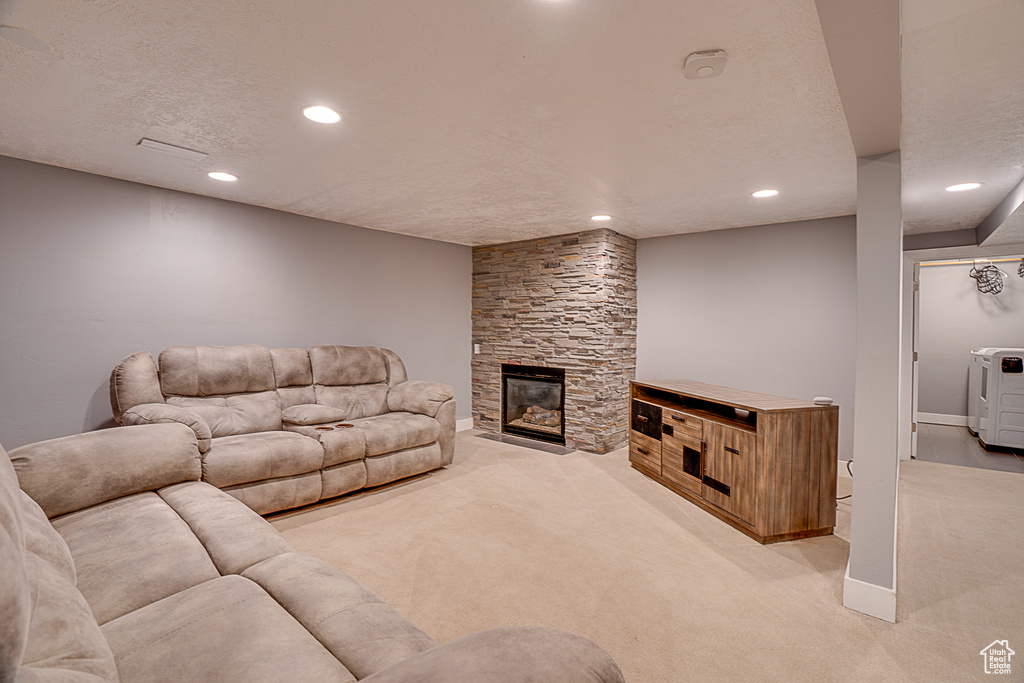 Living room with light colored carpet, a stone fireplace, and a textured ceiling