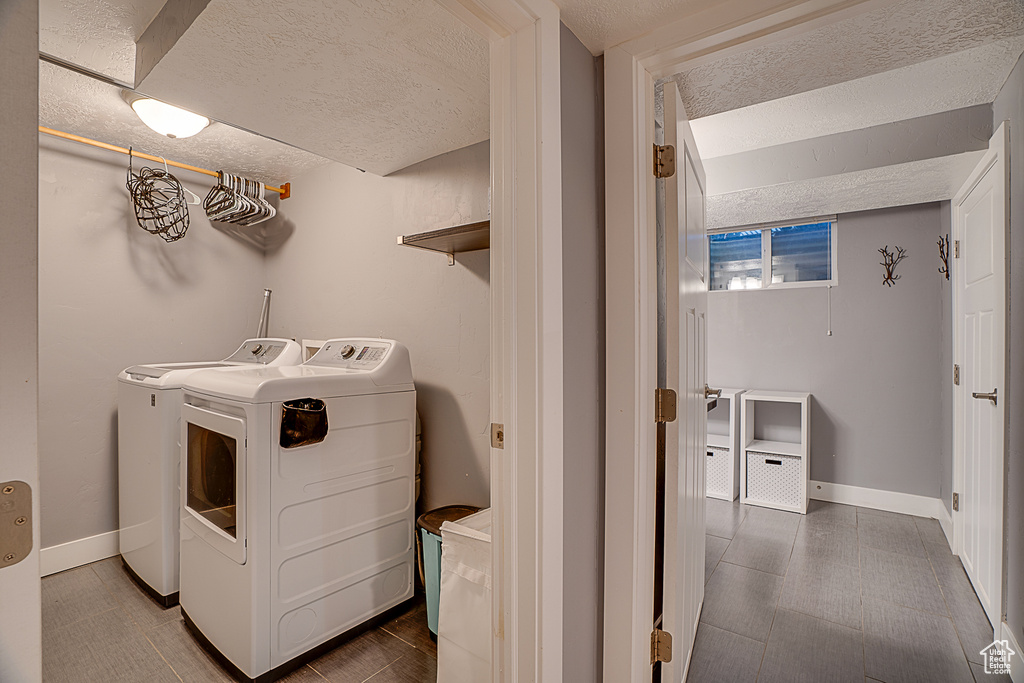 Washroom with a textured ceiling and washer and clothes dryer