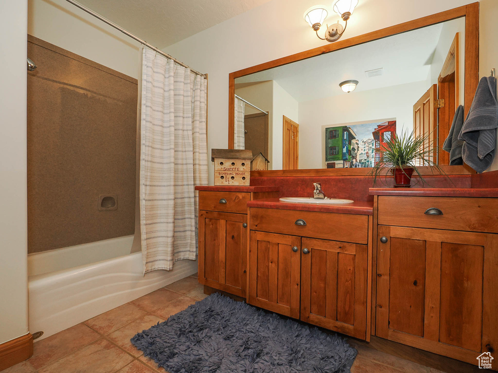 Bathroom featuring vanity with extensive cabinet space, tile flooring, and shower / tub combo with curtain