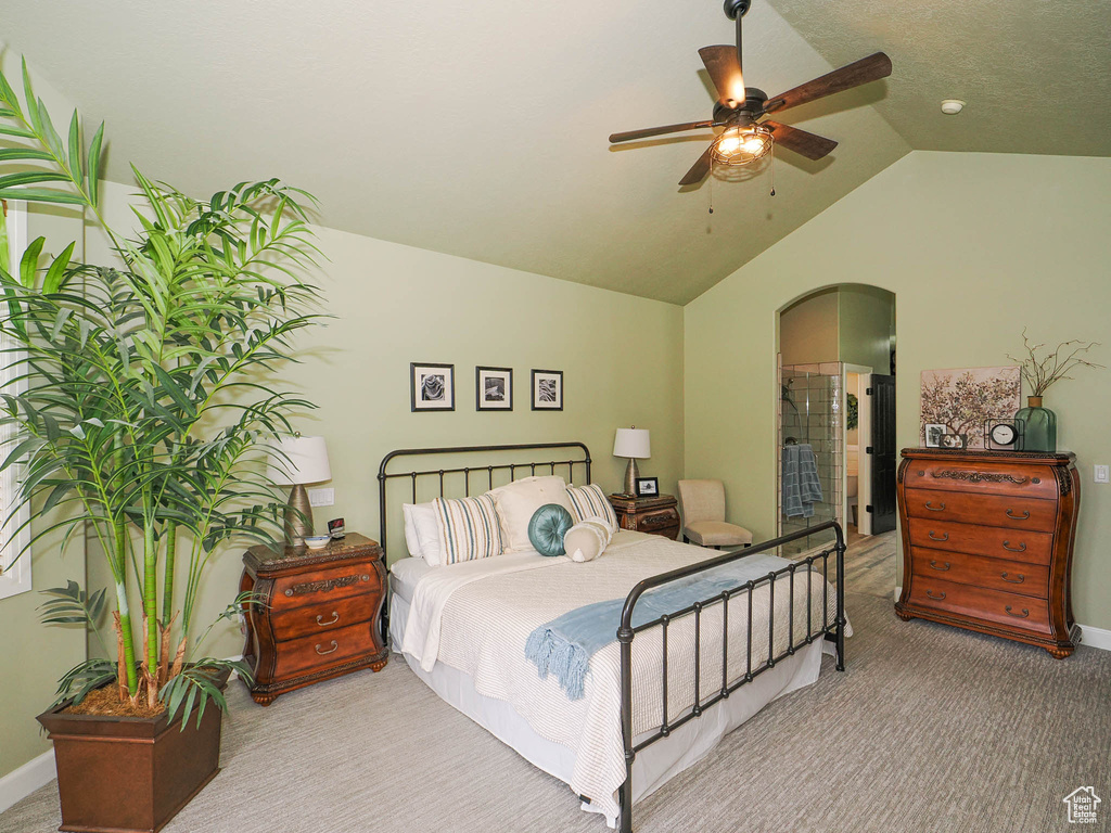 Bedroom with light colored carpet, ceiling fan, vaulted ceiling, and ensuite bathroom
