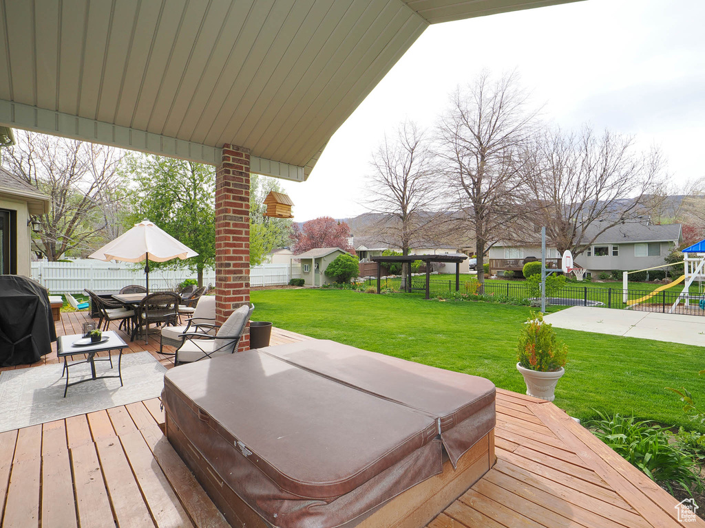 Wooden terrace featuring area for grilling, a patio area, a yard, and a covered hot tub