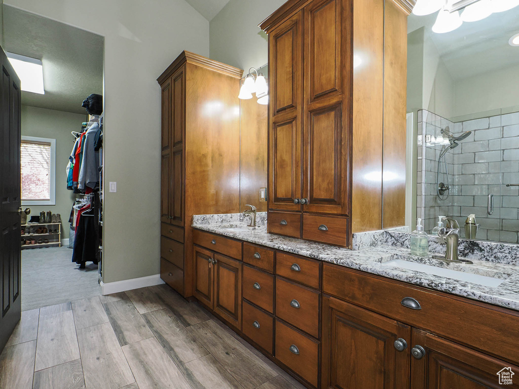 Bathroom featuring double vanity, hardwood / wood-style flooring, and a tile shower