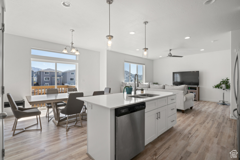 Kitchen with pendant lighting, white cabinets, light hardwood / wood-style flooring, sink, and dishwasher
