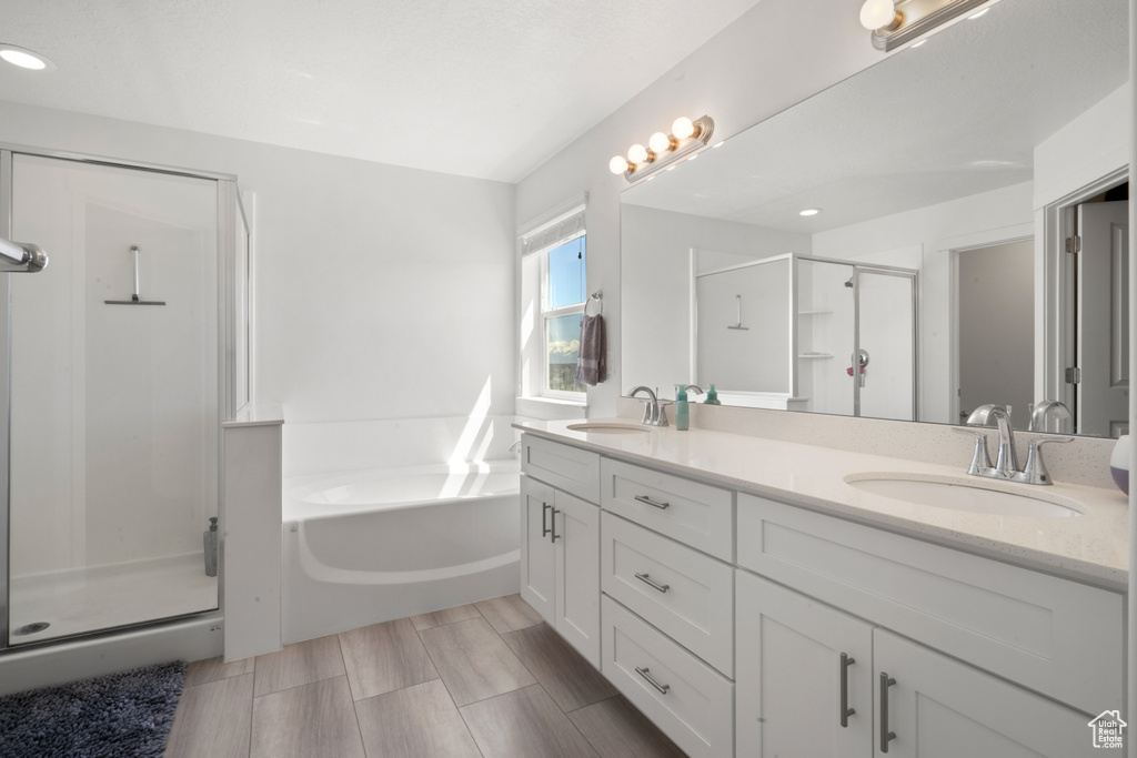 Bathroom featuring dual sinks, shower with separate bathtub, and large vanity