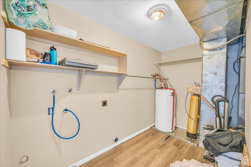 Clothes washing area featuring electric dryer hookup, light wood-type flooring, and electric water heater